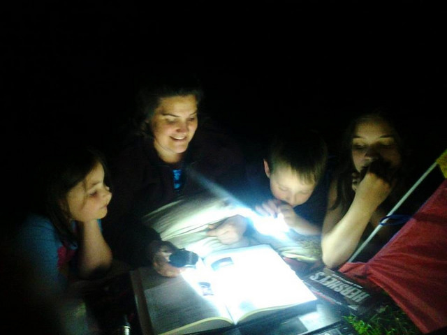 Mom & Kids reading Astronomy book under the stars